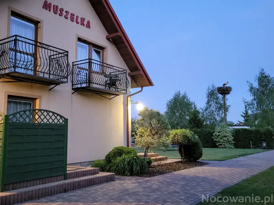 Willa Muszelka w Dębkach wieczorem — elewacja z balkonami i zadbany ogród