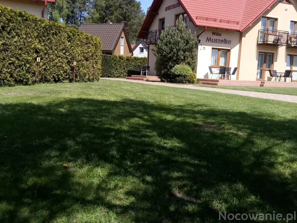 Widok na Willę Muszelka w Dębkach od strony ogrodu z zielonym trawnikiem