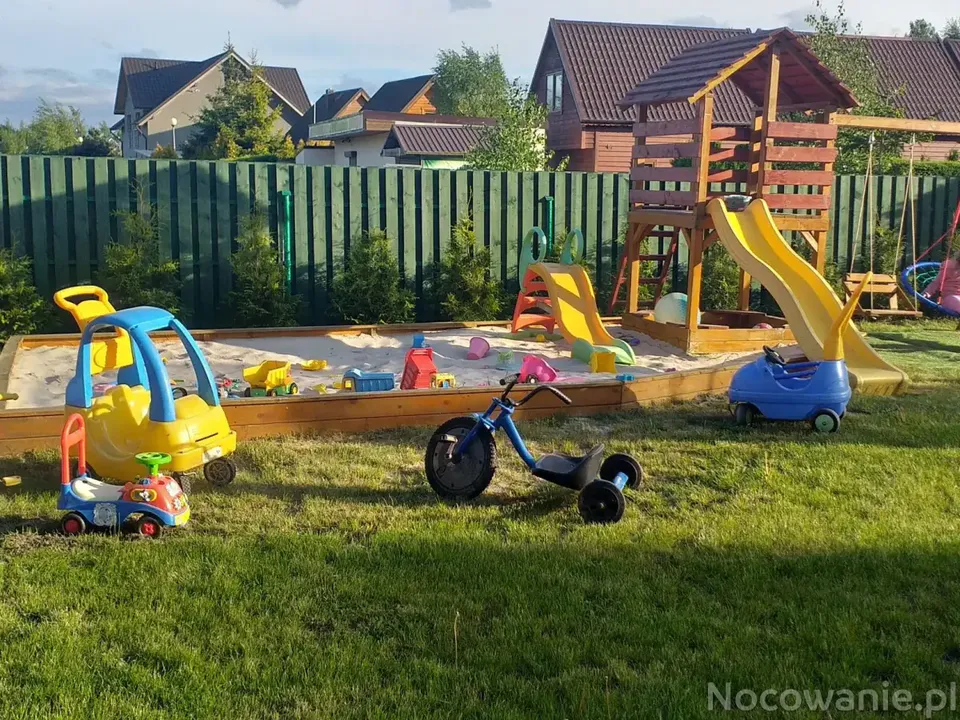 Plac zabaw z drewnianą wieżą, zjeżdżalnią i piaskownicą w ogrodzie Willi Muszelka